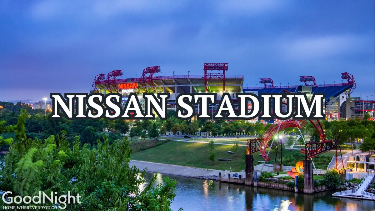 A vibrant exterior scene featuring Nissan Stadium along the riverfront park, with the Nashville city skyline rising in the background. The image captures people enjoying the energetic atmosphere—possibly attending a sports game, having a picnic in the park, or walking along the river under a scenic sunset.