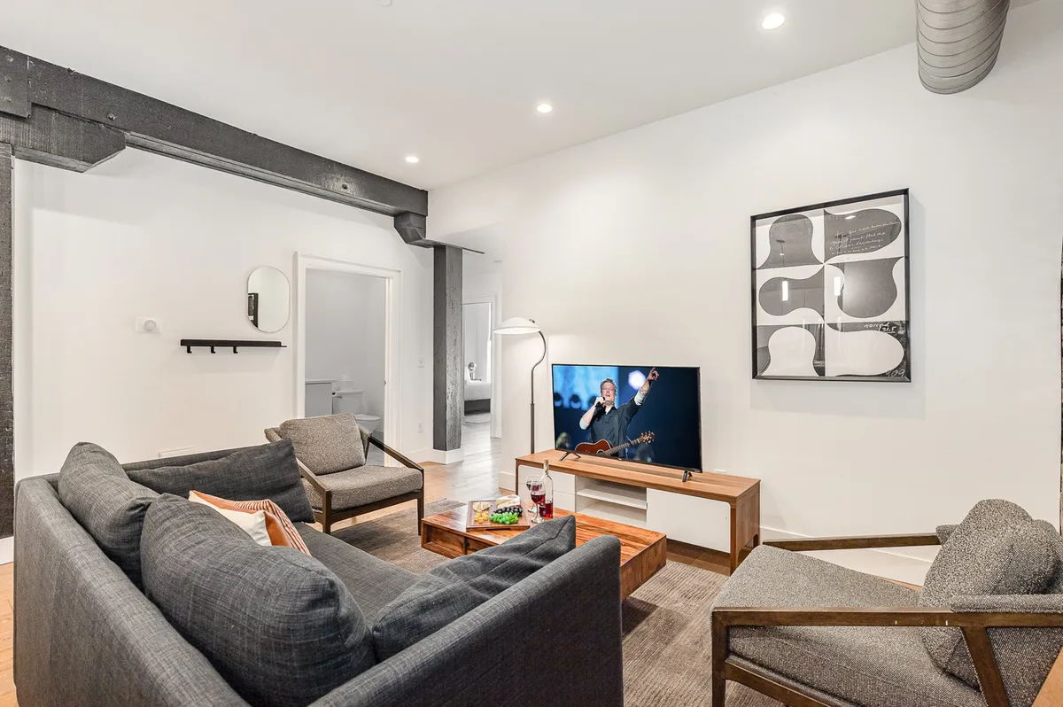 A comfortable living area with a sofa, coffee table, television, and colorful artwork, perfect for relaxing, socializing, or using as an additional sleeping area with sleeper sofas.